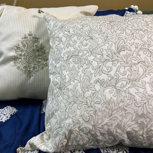 two cushions with gold embroidary on the navy blue sofa throw