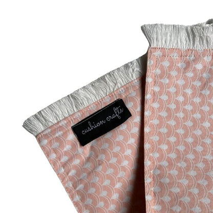 The corner of the Peach Cotton Printed Placemats with tassles and brand tag